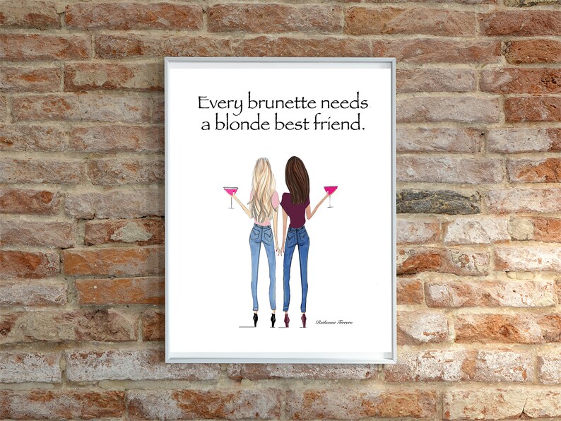 Puede incluir: Una impresi&oacute;n enmarcada en blanco con una cita que dice "Every brunette needs a blonde best friend." La impresi&oacute;n presenta una ilustraci&oacute;n de dibujos animados de dos mujeres, una con cabello rubio y otra con cabello casta&ntilde;o, ambas con jeans y sosteniendo c&oacute;cteles rosados.