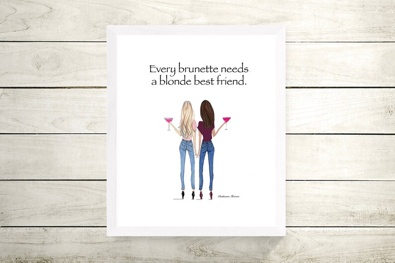 Puede incluir: Una impresi&oacute;n enmarcada en blanco con una cita que dice "Every brunette needs a blonde best friend." La impresi&oacute;n presenta una ilustraci&oacute;n de dibujos animados de dos mujeres, una con cabello rubio y otra con cabello casta&ntilde;o, sosteniendo c&oacute;cteles rosados.
