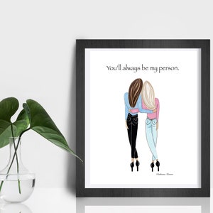 K&ouml;nnte beinhalten: Gerahmter Kunstdruck mit einer Illustration von zwei Figuren, die sich umarmen. Eine hat braunes Haar und ein blaues Oberteil, die andere hat blondes Haar und ein rosa Oberteil. Der Text lautet: &bdquo;Du wirst immer meine Person sein.&ldquo;