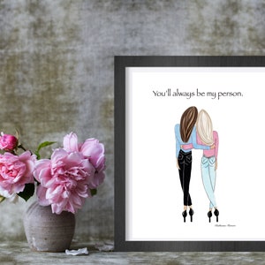 K&ouml;nnte beinhalten: Gerahmter Kunstdruck mit einer Illustration von zwei sich umarmenden Frauen. Der Text "You'll always be my person" steht &uuml;ber der Illustration. Links ist eine Vase mit rosa Blumen.