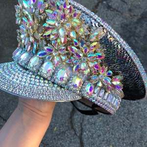 May include: A silver and black sequined hat with iridescent rhinestones and flower-shaped embellishments.
