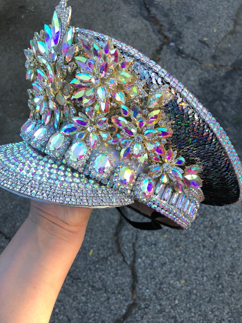 May include: A silver and black sequined hat with iridescent rhinestones and flower-shaped embellishments.
