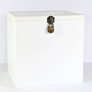 Op de afbeelding: Witte houten doos met een gleuf aan de bovenkant en een messing slot met een sleutelgat.