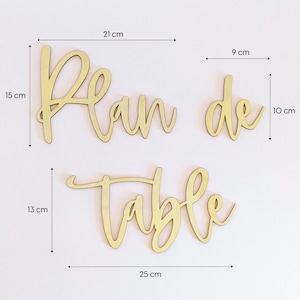 May include: Wooden sign with the words "Plan de Table" in a cursive font. The sign is 21 cm wide, 15 cm tall, and 13 cm high.