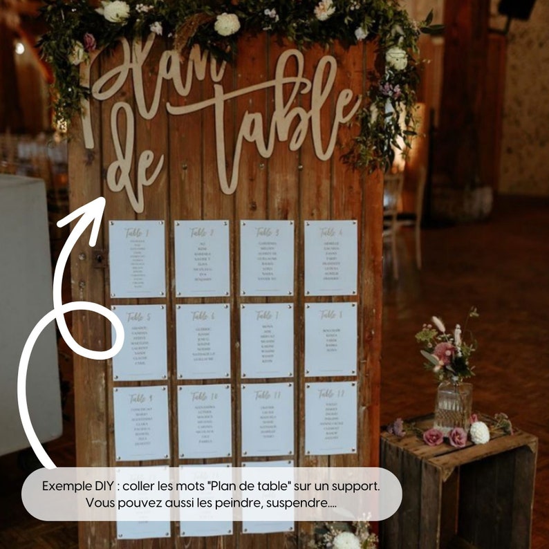 May include: A wooden sign with the words "Plan de table" written in cursive. The sign is decorated with greenery and flowers. There are 12 white cards attached to the sign, each with a table number and a list of names.