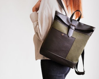 Könnte beinhalten: Ein Rolltop-Rucksack aus einer Kombination von dunkelbraunem, strukturiertem Material und olivgrünem Stoff. Die Tasche verfügt über eine Vordertasche mit Druckknopfverschluss, eine obere Klappe mit braunem Riemen und Metallschnalle sowie verstellbare Schultergurte.