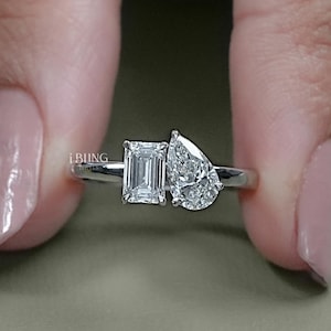 Peut inclure: Une bague en argent avec deux diamants. Le plus grand diamant est de forme poire et le plus petit est de taille émeraude.
