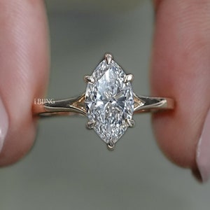 Puede incluir: Un anillo de compromiso de oro con un diamante de forma marquesa. El diamante está engastado en garras y tiene un corte brillante.