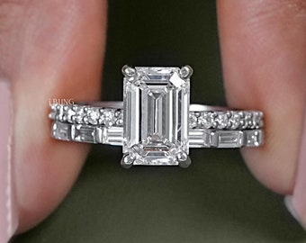 Op de afbeelding: Een zilveren verlovingsring met een grote smaragd geslepen diamant als middelste steen en een bijpassende band met kleinere diamanten.