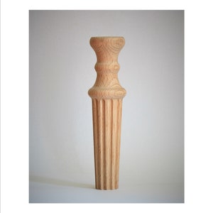 Op de afbeelding: Een houten meubelpoot met een geribbeld ontwerp en een gedraaide bovenkant.