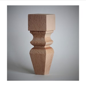 May include: A wooden furniture leg with a square top and a fluted design. The leg is made of light brown wood and has a smooth finish.