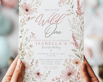 May include: A floral-themed invitation with the text "Wild One" in a cursive font. The invitation includes details for a first birthday celebration, with floral accents in pink and green. The invitation is held by two hands.