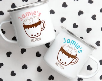 May include: Two white enamel mugs with a silver rim. Both mugs feature a cartoon illustration of a mug of hot cocoa with marshmallows and the text "Jamie's Hot Cocoa". One mug has pink text and the other has blue text.