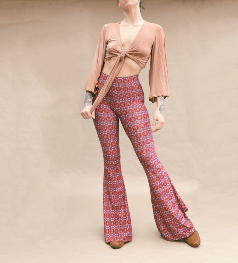 May include: A woman wearing a brown, tie-front top and red and blue patterned bell-bottom pants.