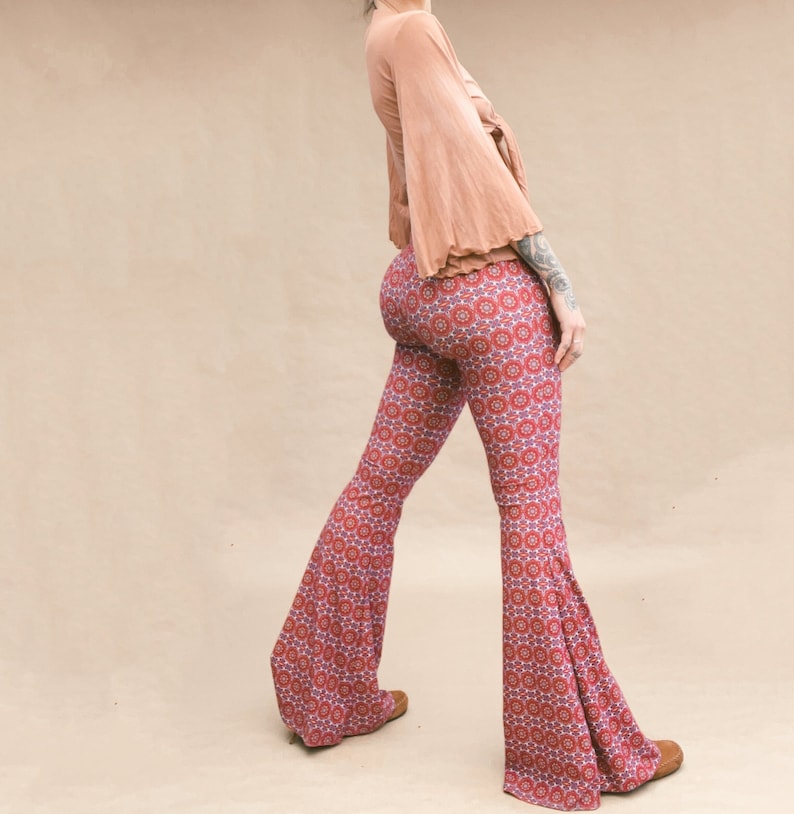 May include: A woman wearing a peach-colored top with bell sleeves and a pair of red and blue patterned bell bottom pants.