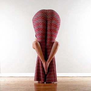May include: A person in red and white patterned pants is bending over with their hands clasped in front of them.