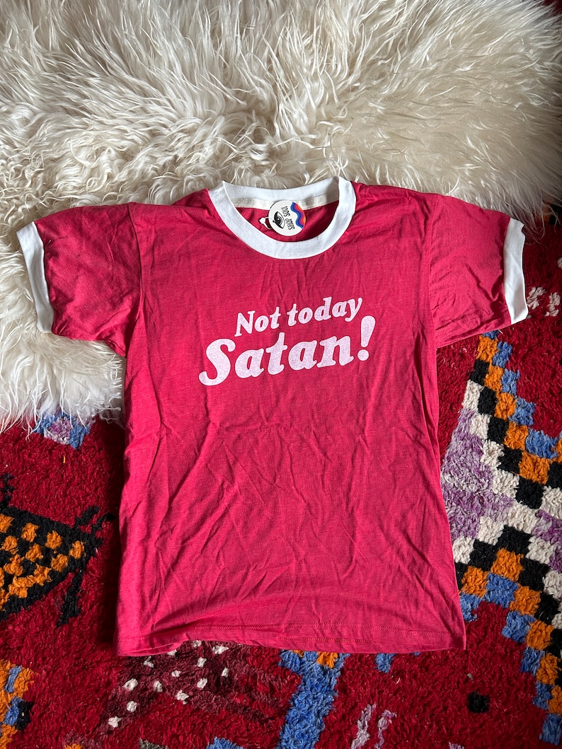 K&ouml;nnte beinhalten: Rotes T-Shirt mit wei&szlig;en Rippen an Kragen und &Auml;rmeln und wei&szlig;em Text "Not today Satan!"