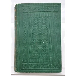 May include: A hardcover book with a dark green cover featuring an embossed geometric pattern. The spine is visible with gold lettering. The book's edges are also gold. The cover has a textured appearance.