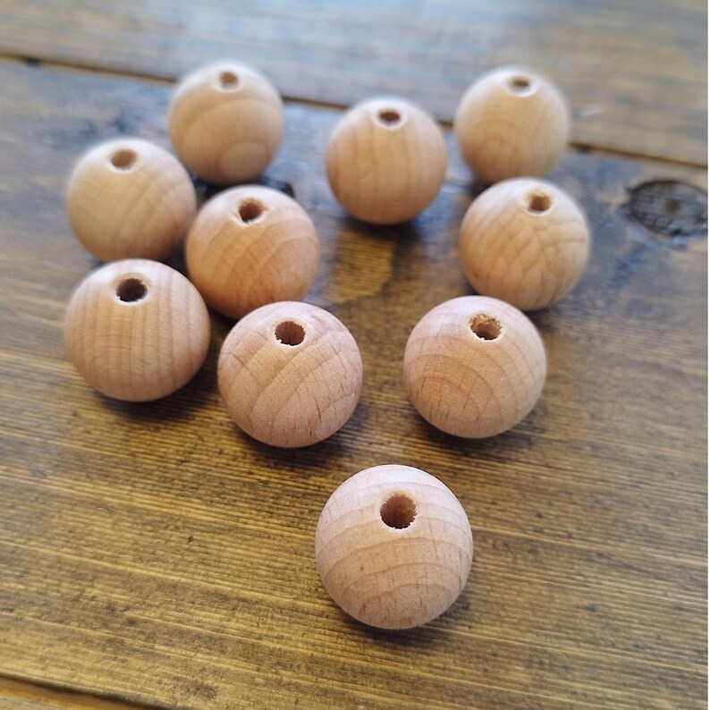 May include: Ten natural wood beads with a hole in the center. The beads are round and smooth, and they are all the same size.