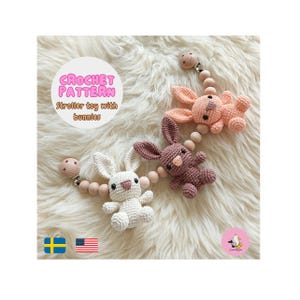 Può includere: Giocattolo per passeggino all'uncinetto con coniglietti bianchi, rosa e malva. I giocattoli sono attaccati a perline e clip di legno. Il testo "CROCHET PATTERN Stroller toy with bunnies" è in un cerchio.