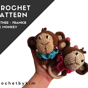 May include: Two crocheted monkey teethers with wooden rings. The monkeys are brown with tan faces and are wearing blue and pink collars. The text "CROCHET PATTERN" and "TEETHER - FRANKIE THE MONKEY" are visible in the upper left corner. The text "crochetbykim" is in the lower left corner.