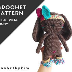 May include: Crochet pattern for a brown tribal bunny with turquoise and pink feathers, a yellow headband, and brown fringe. The pattern is called "Little Tribal Bunny".