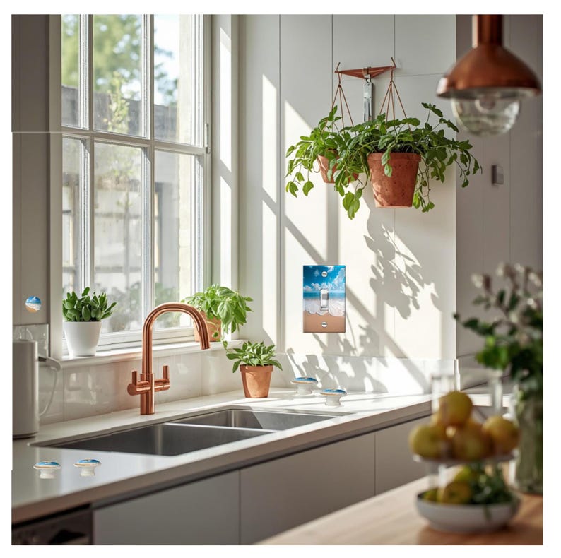 Op de afbeelding: Een moderne keuken met een koperen kraan, dubbele spoelbak en een lichtschakelaar met een strandsc&egrave;ne. Potplanten hangen aan het plafond en staan op de vensterbank. De keuken baadt in natuurlijk licht.