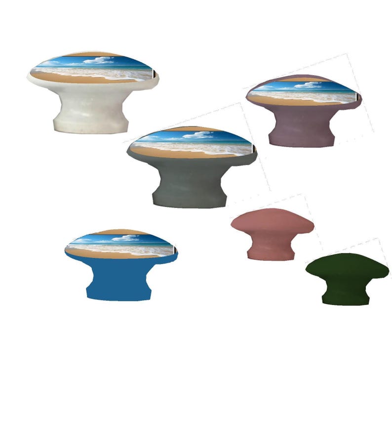 Op de afbeelding: Een verzameling decoratieve kastknoppen in verschillende kleuren, waaronder wit, grijs, blauw, roze en groen. Elke knop heeft een strandsc&egrave;ne met een blauwe lucht, witte wolken en een zandstrand. De knoppen zijn paddenstoelvormig.