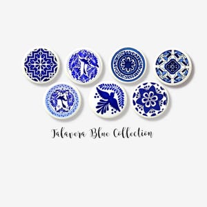 Può includere: Una collezione di sette pomelli per armadietti in ceramica bianca con intricati motivi blu. I disegni includono motivi floreali, geometrici e di uccelli. Il testo "Talavera Blue Collection" è scritto in corsivo sotto.