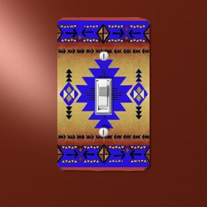 May include: Decorative light switch cover with a Southwestern design. The cover features a blue and gold geometric pattern with a central blue diamond shape and a silver toggle switch. The edges are outlined in red.