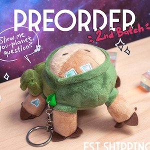 Può includere: Un peluche in un completo con cappuccio verde con dettagli marroni e un portachiavi. I testi "PREORDER" e "2nd Batch" sono visibili. La spedizione stimata è luglio-agosto.