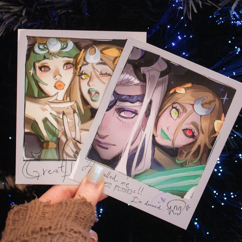 May include: Two polaroid-style prints featuring anime-style illustrations. One print shows three characters with green, yellow, and white accents. The other print shows two characters with purple, green, and yellow accents. Text includes "Great!" and "I'm doomed."