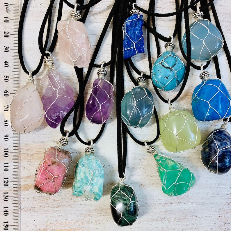 May include: Assortment of 14 colorful gemstone pendants with wire cages, each on a black cord necklace. The stones include amethyst, rose quartz, aquamarine, turquoise, green aventurine, and more.