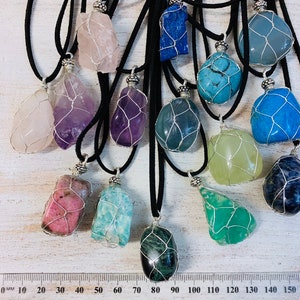 May include: Assortment of 12 wire-wrapped crystal pendants on black cords. The crystals are various colors and shapes, including pink, purple, blue, green, and black.