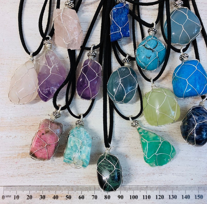 May include: Assortment of 12 wire-wrapped crystal pendants on black cords. The crystals are various colors and shapes, including pink, purple, blue, green, and black.