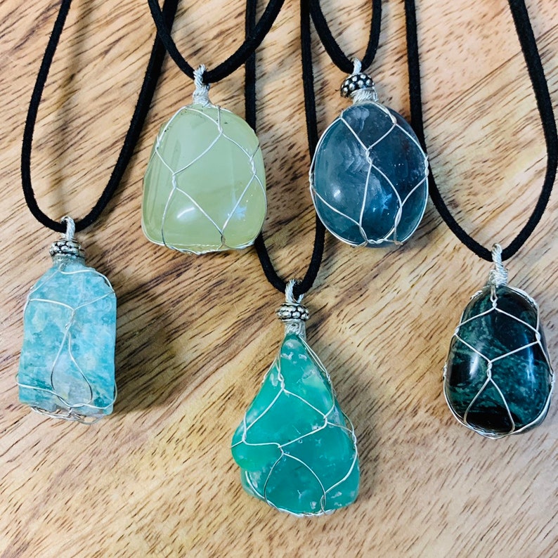 May include: Five wire-wrapped gemstone pendants on black cords. The pendants are made of aquamarine, green aventurine, fluorite, and green moss agate.