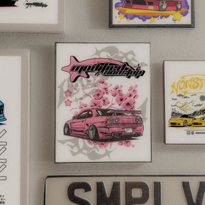 May include: A pink Nissan Skyline R34 with a white and gray graphic design featuring a stylized fish and cherry blossoms. The text "modified nonstop" is printed on the graphic.