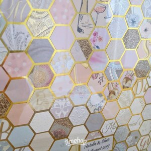 May include: A hexagonal guest book with a gold frame and a pink, white and gold patterned design. The text "Natalie & Chris Married August 2017" is printed on the bottom of the guest book.