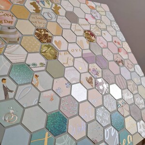 May include: A hexagonal wedding card with a light blue, green and pink colour scheme. The card is made up of many small squares with different patterns and designs. The text on the card includes "Wedding Day" and "For the Love".
