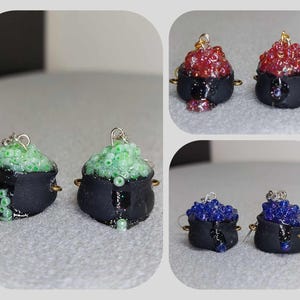 May include: Four pairs of cauldron earrings, each with a different color of glitter inside. The colors are green, red, blue, and purple. The cauldrons are black and have a silver hook.
