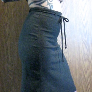 May include: A dark gray skirt with a tie at the waist.