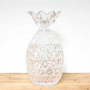 May include: A clear glass pineapple-shaped vase with a textured surface.