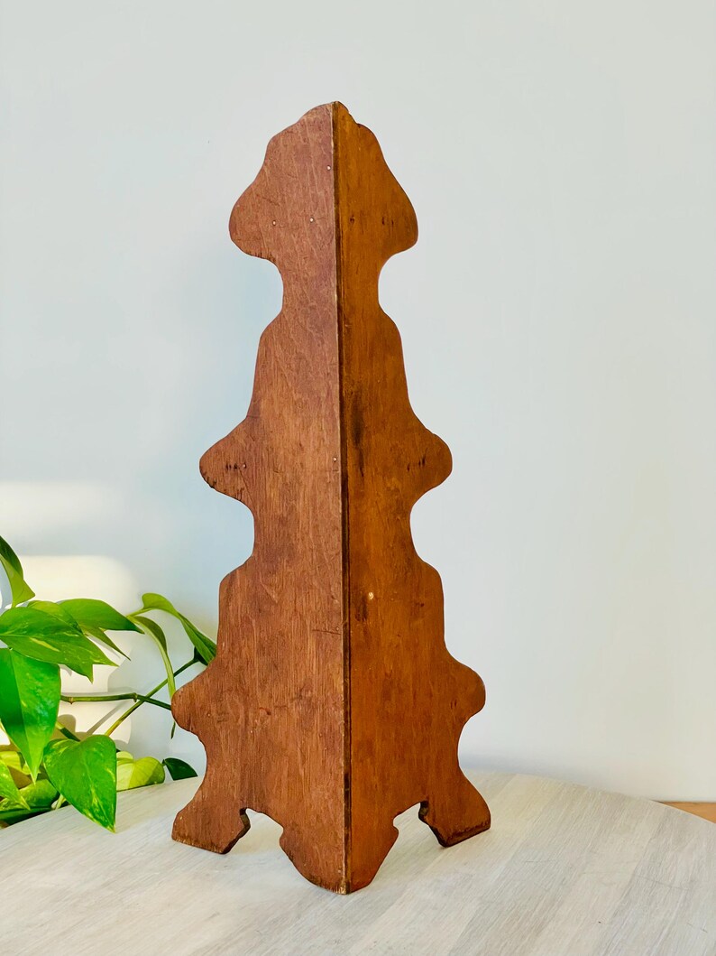 K&ouml;nnte beinhalten: Ein Vintage-Ausstellungsst&auml;nder aus Holz mit warmbraunem Finish. Der St&auml;nder hat ein einzigartiges, symmetrisches Design mit mehreren Ebenen und einer dekorativen Oberseite. Er wird wahrscheinlich zum Ausstellen von Gegenst&auml;nden verwendet.
