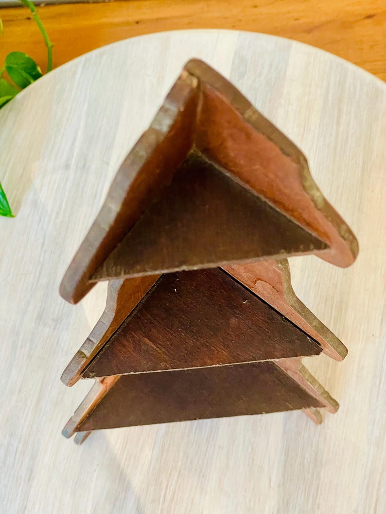 K&ouml;nnte beinhalten: Ein Weinregal aus Holz mit dreieckigem Design. Das Regal besteht aus dunkelbraunem Holz und hat drei Ebenen. Die Kanten des Regals sind hellbraun.