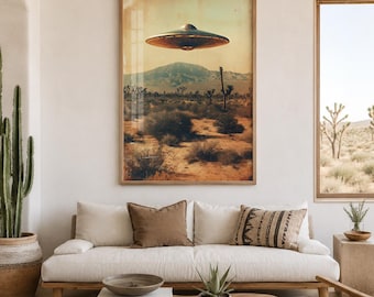 May include: A framed wall art print depicting a metallic flying saucer hovering over a desert landscape with mountains and cacti under a warm, hazy sky. The artwork is displayed in a living room setting above a white sofa with various throw pillows.