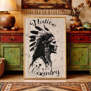 May include: A rectangular framed wall art print featuring a black and white ink-style illustration of a person wearing a feathered headdress in profile. The text "Native Country" is printed in a stylized black script font above and below the portrait.