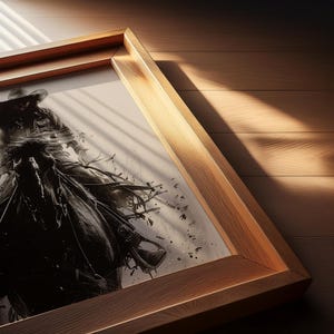 May include: A framed black and white illustration of a person wearing a cowboy hat riding a horse. The artwork is encased in a light-toned wooden frame with a visible grain texture, positioned at an angle to show depth and detail.