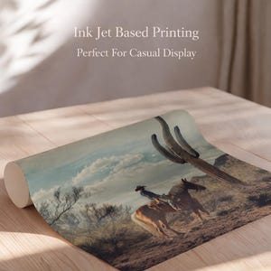 May include: Rolled print featuring a cowboy riding a horse through a desert landscape with a large cactus. The print has a vintage aesthetic with a muted color palette. Text on the print reads "Ink Jet Based Printing Perfect For Casual Display."