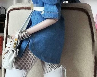 May include: A fashion doll with long red hair wearing a blue denim shirt, white fishnet stockings, and white thigh-high boots. The doll is sitting on a light brown chair in front of a white shelf with various accessories.