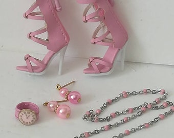 May include: Pink high-heeled sandals with a delicate strap design, a silver chain necklace with pink beads, a pair of pink earrings, and a small pink and silver watch.